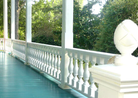 A white railing on a porch with a white fence, creating a clean and cohesive look.