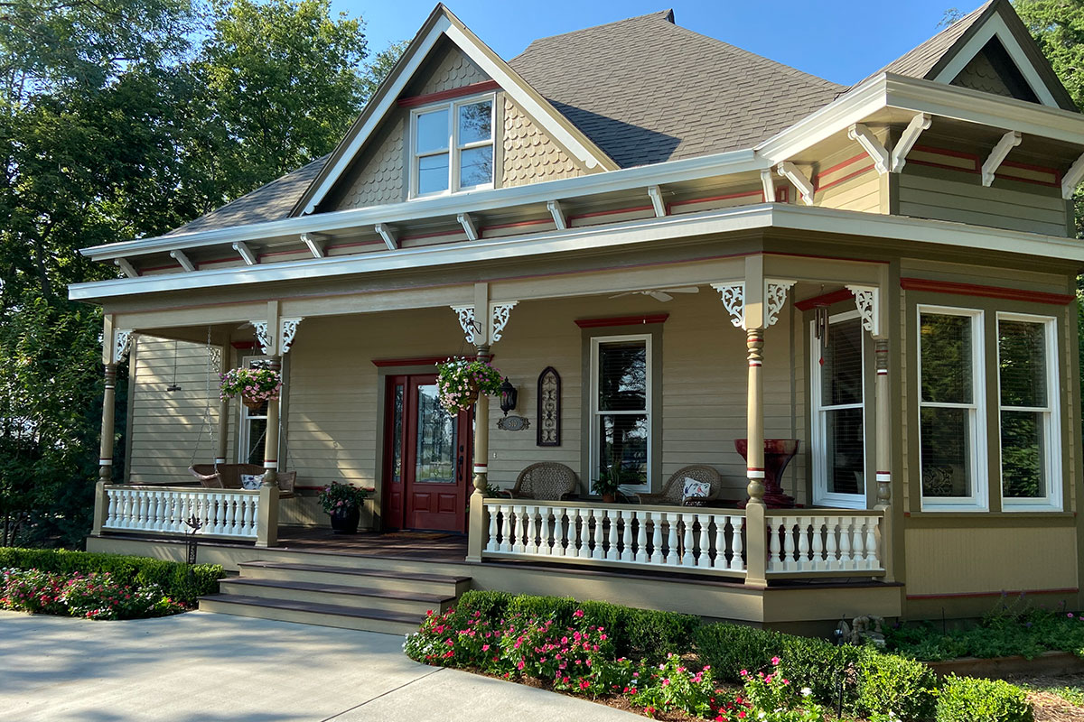 A house with a porch and a front porch, surrounded by greenery and a well-maintained garden.