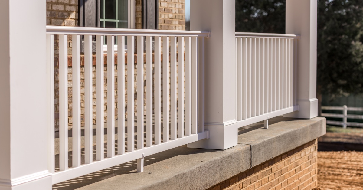 The exterior of a brick building with three large columns and two sections of white porch posts between the columns.