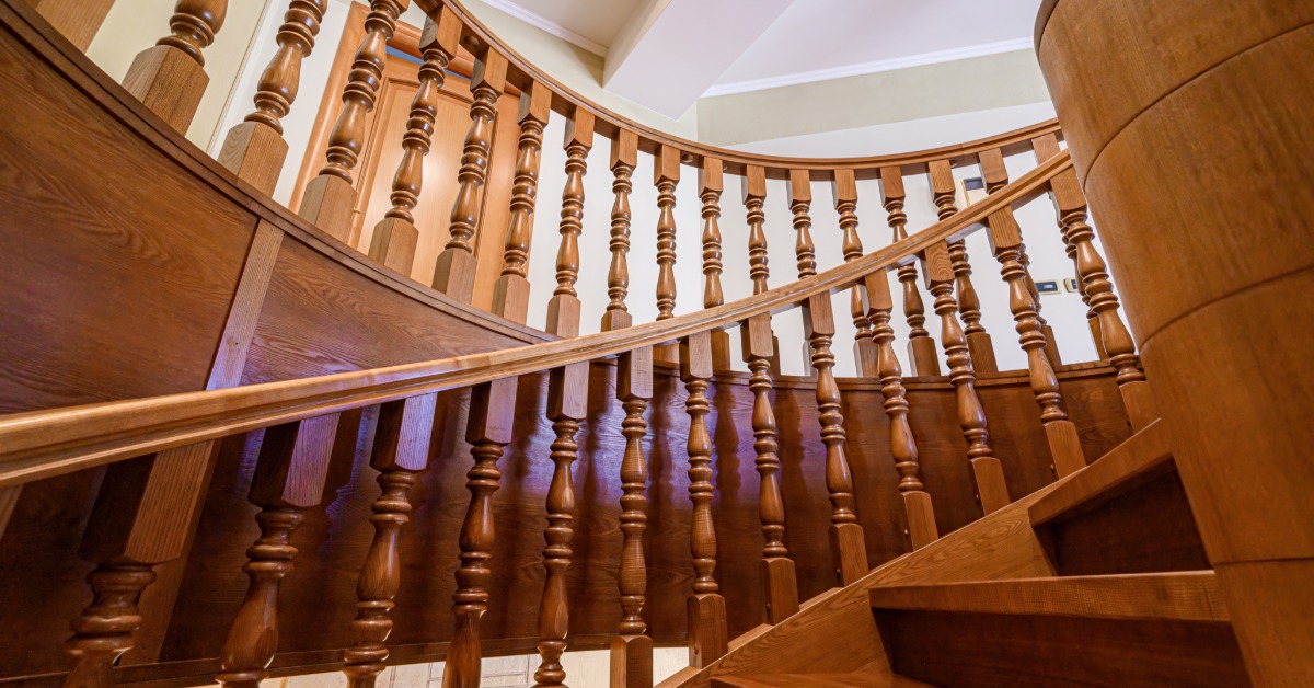 A curved wooden staircase features custom-turned spindles that add classic architectural detail throughout the railing.
