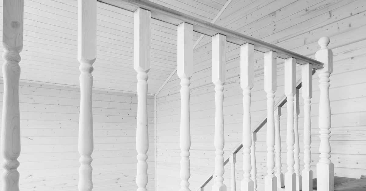 White turned wood balusters line a covered porch railing, creating a traditional architectural look along the exterior.