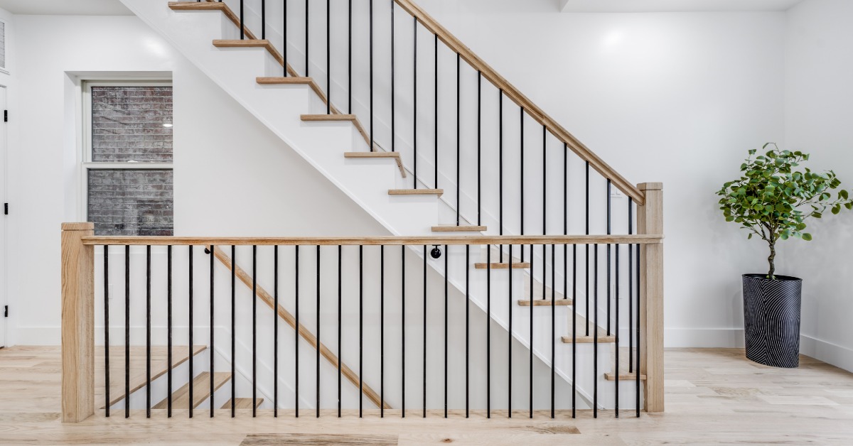 A modern staircase features a wood handrail with black metal balusters, creating a clean contrast along the railing.